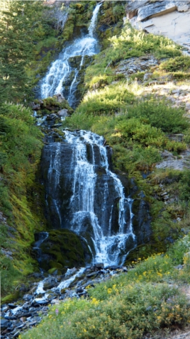 [Two photos stitched vertically to show several different elevation drops the water takes as it moves down the hillside in several streams which converge and diverge from each other. There is greenery on either side of the fall area which does a zig zag down the hill.]